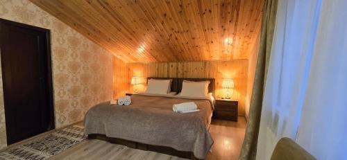 a bedroom with a bed with a wooden ceiling at Guest House Tamta in Stepantsminda