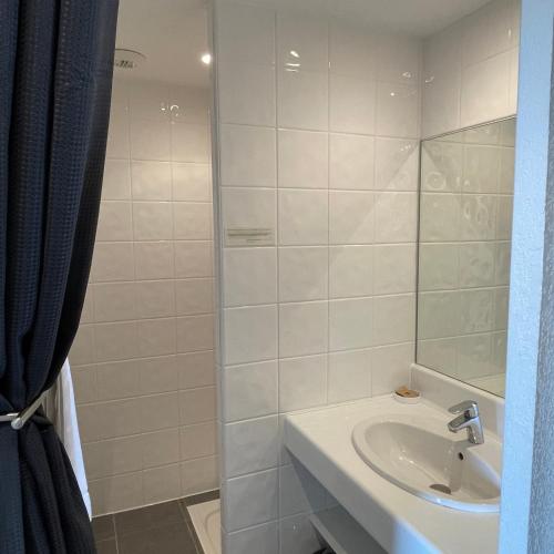 a white bathroom with a sink and a mirror at Patio De Violette in Uzès