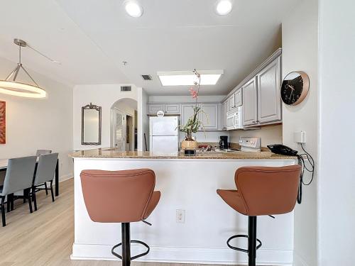 a kitchen with white cabinets and a bar with chairs at Beautiful Orlando Lakefront Condo 5 MINUTES FROM DISNEY in Orlando