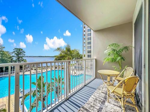 a balcony with a table and chairs and a swimming pool at Beautiful Orlando Lakefront Condo 5 MINUTES FROM DISNEY in Orlando