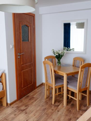a dining room with a wooden table and chairs at Willa Ada Pokoje & Apartamenty in Karwia