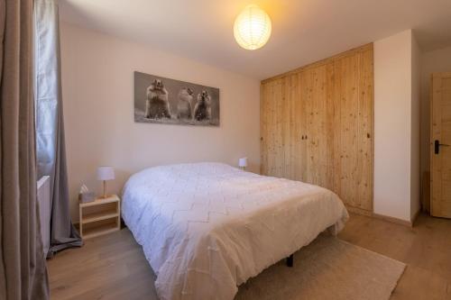 ein Schlafzimmer mit einem weißen Bett und einer Holztür in der Unterkunft T3 entièrement rénové, à 3 minutes des pistes in La Salle Les Alpes