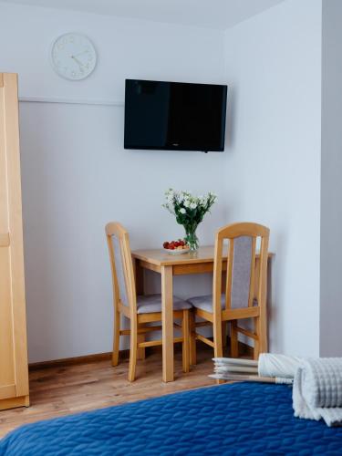 a dining room table with two chairs and a tv at Willa Ada Pokoje & Apartamenty in Karwia