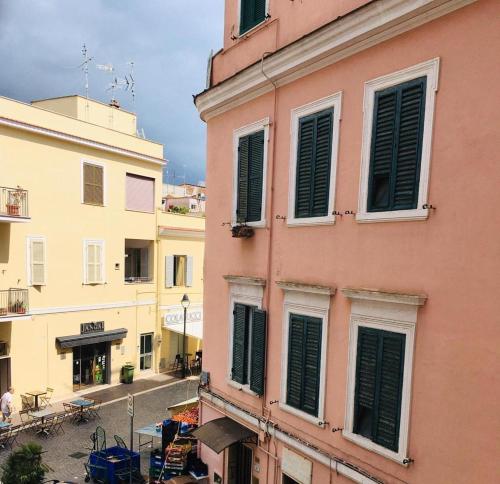 a pink building with green shutters on a street at A due passi dal mare 2023 in Nettuno