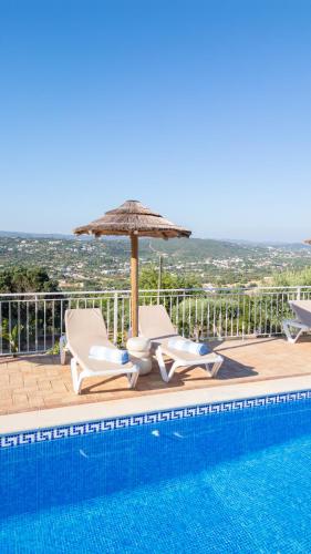 a swimming pool with two chairs and an umbrella at Casa Quadra Dique in Faro