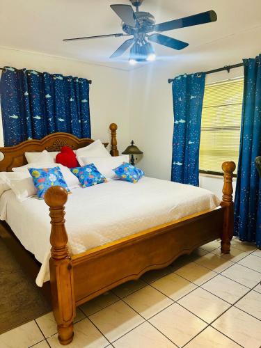 a bedroom with a bed with blue curtains and a ceiling fan at Love Story Pool House, free parking & BBQ in Miami