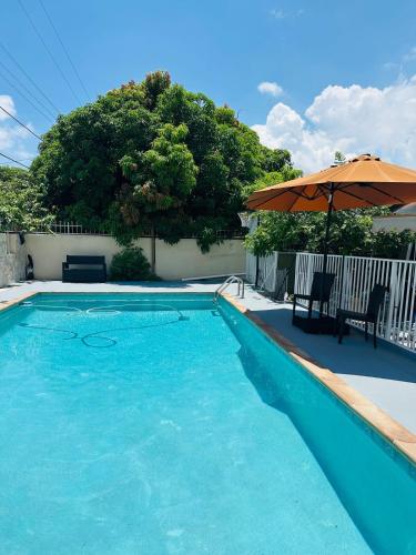 a large blue swimming pool with an umbrella at Love Story Pool House, free parking & BBQ in Miami