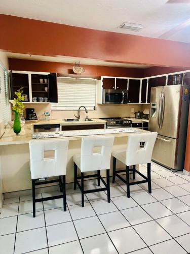 a kitchen with white chairs and a stainless steel refrigerator at Love Story Pool House, free parking & BBQ in Miami