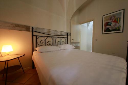 a bedroom with a white bed and a table with a lamp at Apt 5 Borgo Lago di Garda in Lonato del Garda