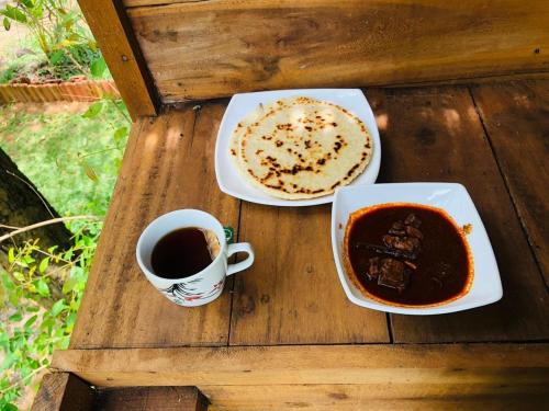 a table with two plates of food and a cup of coffee at Wisdom Bungalow- Habarana in Moragaswewa