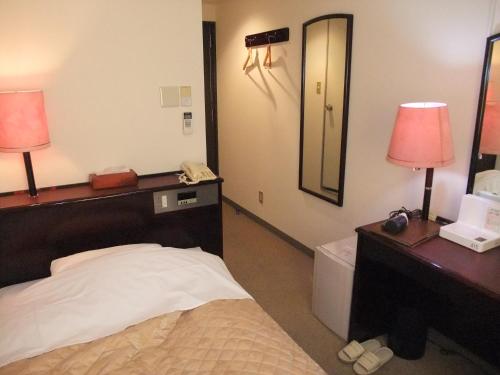 a hotel room with a bed and a mirror at Hotel New Takahashi Kouyadai in Tsukuba