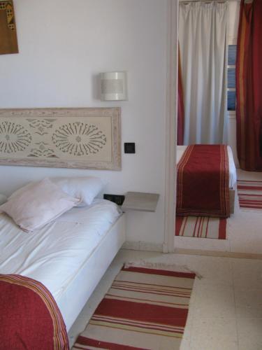 a small bedroom with a bed and a mirror at Dar Salem in Djerba