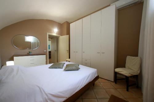 a bedroom with a white bed and a chair at Apt 6 Borgo Lago di Garda in Lonato del Garda