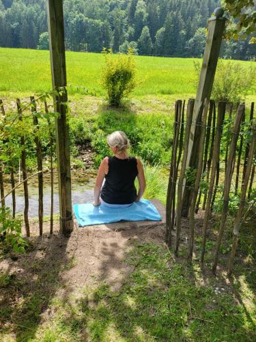 a woman sitting on a blanket in front of a fence at Ferienwohnungen beim Silbergersee in Oberaudorf