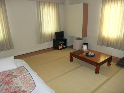 a living room with a bed and a coffee table at Hotel New Takahashi Kouyadai in Tsukuba