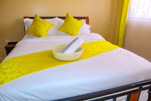 een bed met een gele deken en een mand erop bij Kings Square Tebiz Haven in Eldoret