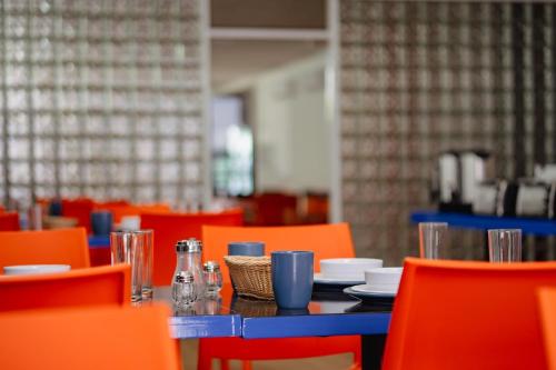 a dining room with a blue table and orange chairs at Hotel WW in Mérida