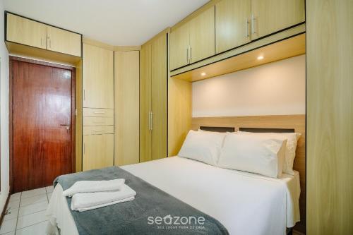 ein Schlafzimmer mit einem großen weißen Bett und einem Schrank in der Unterkunft Condomínio bem localizado a 100m da Praia - CSC in Florianópolis