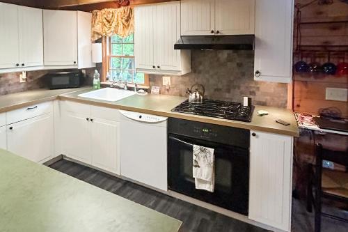 a kitchen with white cabinets and a black stove top oven at Wandering Trails Retreat in Cambridge