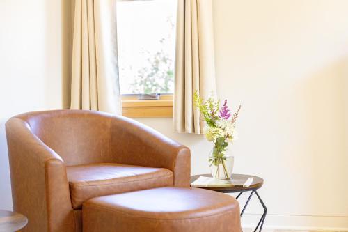 a brown chair sitting next to a window with a table at The Mercer House in Stowe