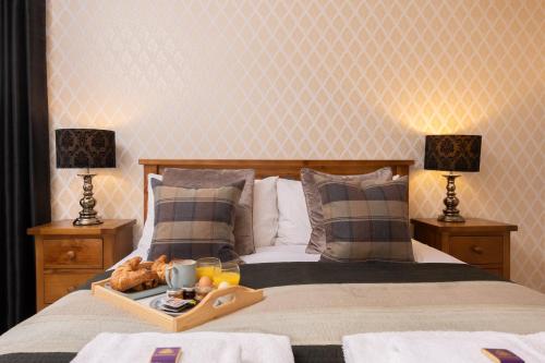 a tray of food on a bed with two lamps at The Highland Club in Fort Augustus