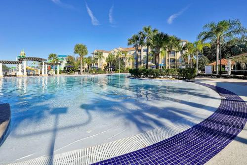 a swimming pool at a resort with palm trees and buildings at Mickey's Welcome Inn - Closest Resort to Disney in Orlando