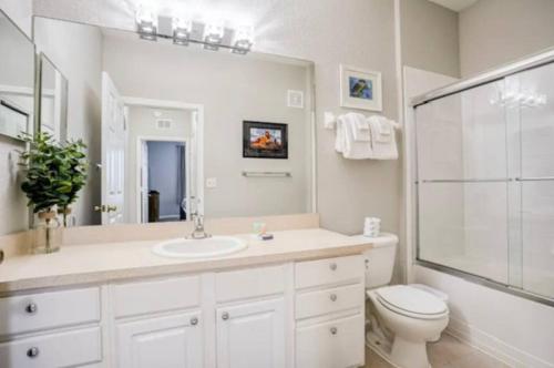 a bathroom with a sink and a toilet and a mirror at Mickey's Welcome Inn - Closest Resort to Disney in Orlando