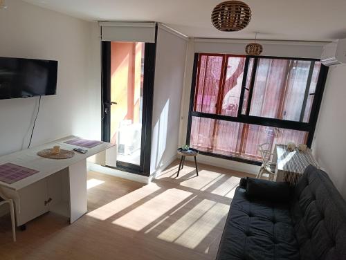 a living room with a couch and two large windows at Apartamento en el City Center de Montevideo in Montevideo