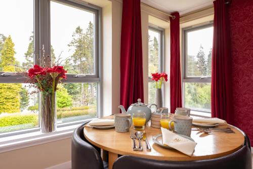 a dining room with a table with chairs and windows at The Highland Club in Fort Augustus