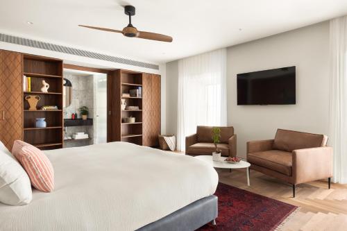 a bedroom with a bed and a tv and chairs at Hotel RECEPTION in Tel Aviv