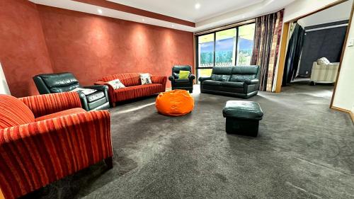 a living room with leather furniture and an orange pillow at Spacious 5BR Family Escape on Busch Lane in Christchurch