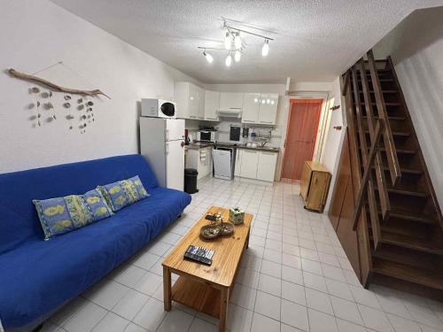 un salon avec un canapé bleu et une table dans l'établissement Pavillon Duplex T2/terrasse, au Cap d'Agde