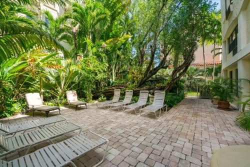 a group of chairs sitting on a patio with trees at Coastal View Terrace in Palm Beach