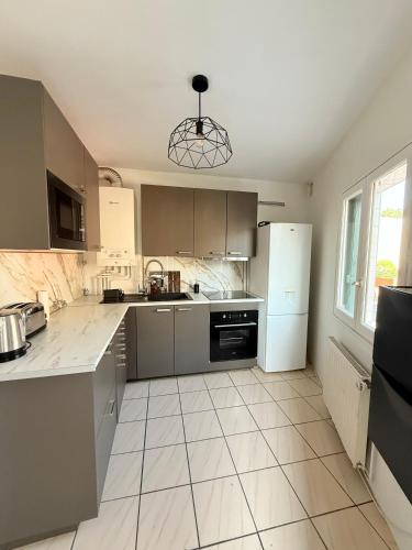 - une cuisine avec des appareils en acier inoxydable et du carrelage blanc dans l'établissement Charmante Maison indépendante T3, à Suresnes