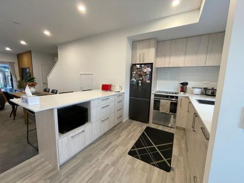 a kitchen with white cabinets and a black refrigerator at Cosy and Central Family Home in Christchurch