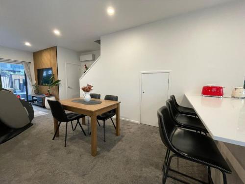 a dining room with a table and black chairs at Cosy and Central Family Home in Christchurch