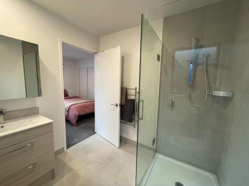 a bathroom with a shower and a sink and a bed at Cosy and Central Family Home in Christchurch