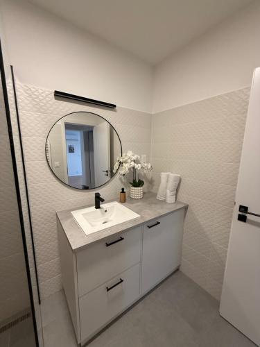 a bathroom with a sink and a mirror at Dream Premium Apartman in Mosonmagyaróvár