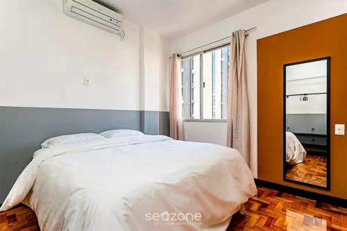 a bedroom with a white bed and a mirror at Practical Apt in Downtown 350m SC Museum CAT406 in Florianópolis