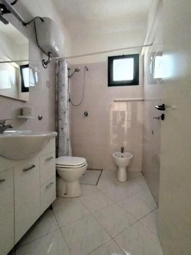 a white bathroom with a toilet and a sink at Villette Mar Ionio in Nardò