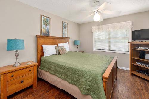 a bedroom with a bed with a green comforter and a television at Harbour Oaks #508 in Saint Simons Island