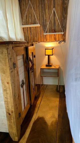a bedroom with a bed and a table with a lamp at Mano a Mano Eco Hostal in Las Peñitas