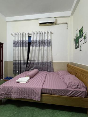 a bedroom with a bed with purple sheets and a window at Motel Hoàn Chun in Can Tho
