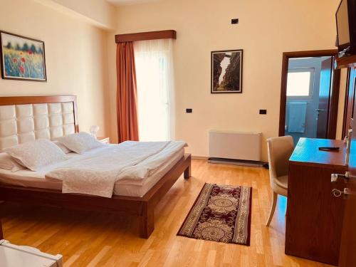 a bedroom with a bed and a desk and a window at Hotel Kanione in Çorovodë