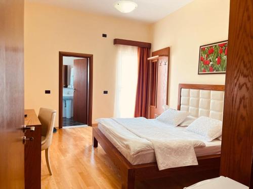 a bedroom with a bed and a desk and a window at Hotel Kanione in Çorovodë