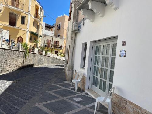 two chairs sitting outside of a white building at Via Roma 55 in Lipari