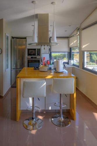 a kitchen with a counter and two bar stools at Mytilini luxury pool VILLA AMIKA in Mytilini