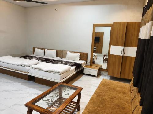 a bedroom with two beds and a table in it at Hotel Anmol and Resort in Ghāt Bilod