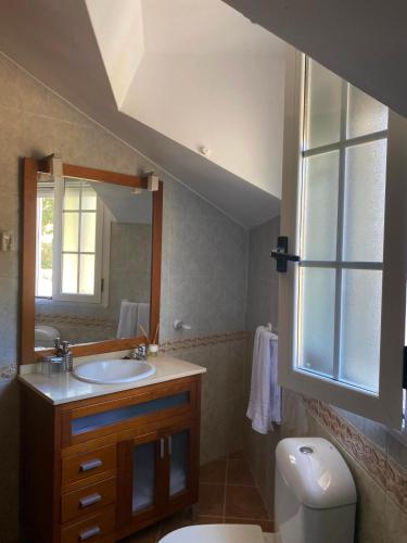 a bathroom with a sink and a toilet and a mirror at Casa Rural La Abuela Obdulia in Piornal
