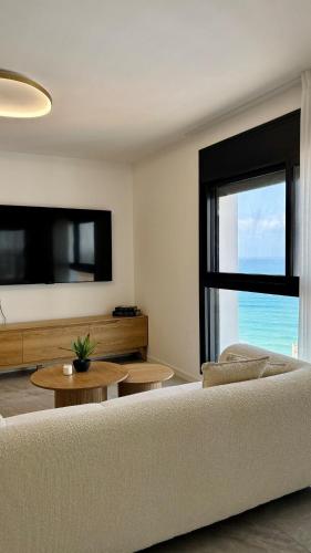 a living room with a white couch and a large window at Blue Bay in Netanya